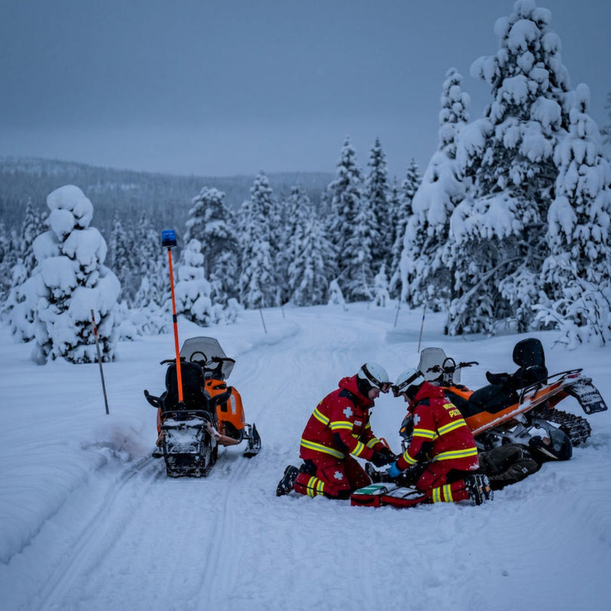 kaksi SkiPatrol henkilöä auttaa loukkaantunutta moottorikelkkailijaa